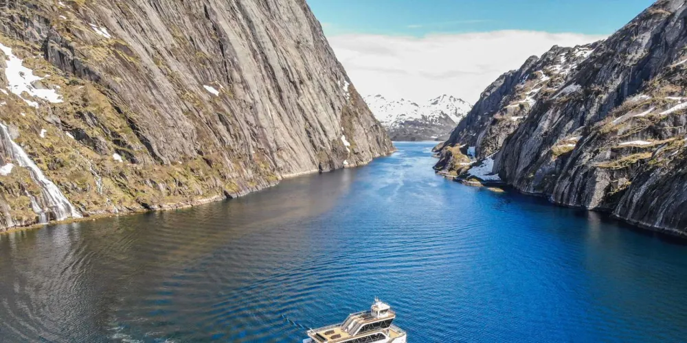 Steep granite walls of Trollfjord mirrored in the calm green water