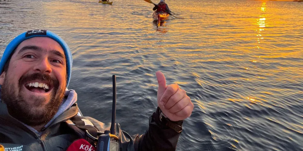A guest grinning mid-paddle on the midnight sun kayak tour
