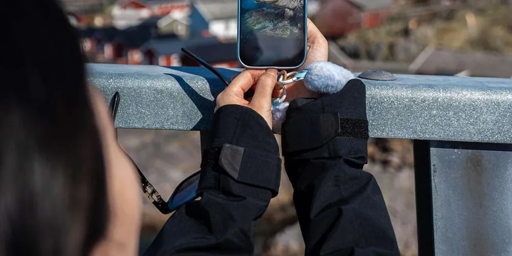 A guest photographing the Lofoten landscape over a bridge railing